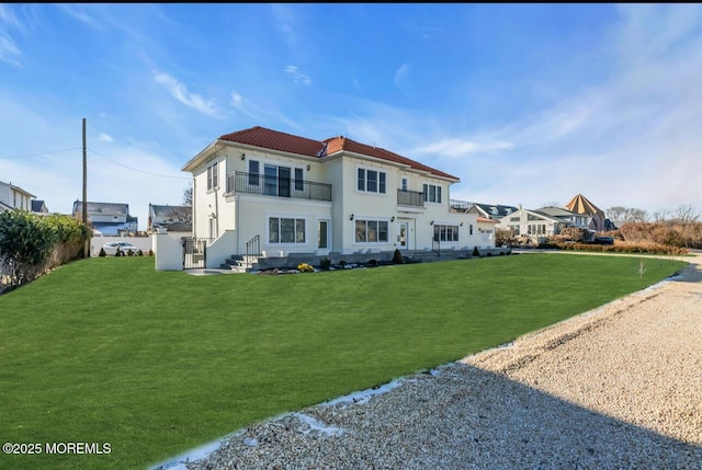 rear view of property with a balcony and a yard