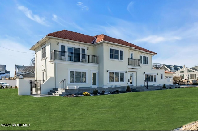 rear view of house featuring a yard and a balcony