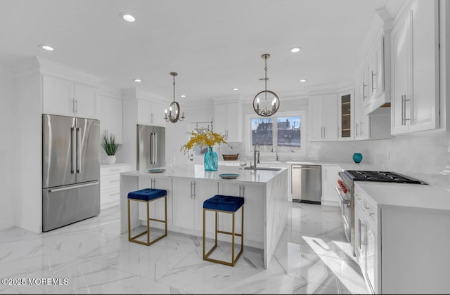 kitchen featuring pendant lighting, white cabinets, high quality appliances, and a center island with sink