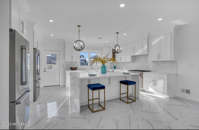 kitchen featuring white cabinetry, premium appliances, ornamental molding, a kitchen island with sink, and a notable chandelier