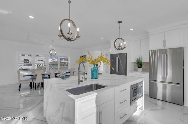 kitchen featuring white cabinetry, stainless steel appliances, a chandelier, and a kitchen island with sink