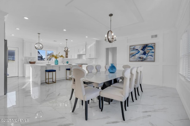 dining space with sink, crown molding, and a chandelier