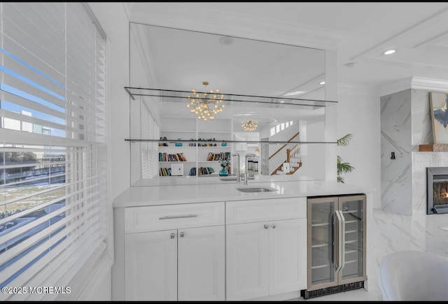 bar featuring sink, crown molding, a premium fireplace, white cabinets, and beverage cooler