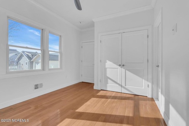 unfurnished bedroom with ornamental molding, a closet, ceiling fan, and light wood-type flooring