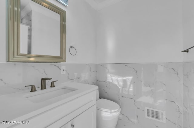 bathroom with vanity, tile walls, and toilet