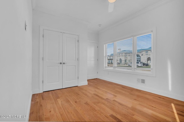 unfurnished bedroom featuring crown molding, a closet, ceiling fan, and light wood-type flooring