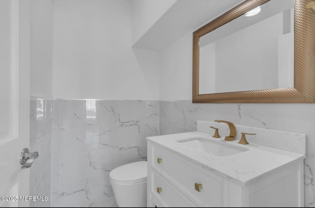 bathroom featuring vanity, toilet, and tile walls