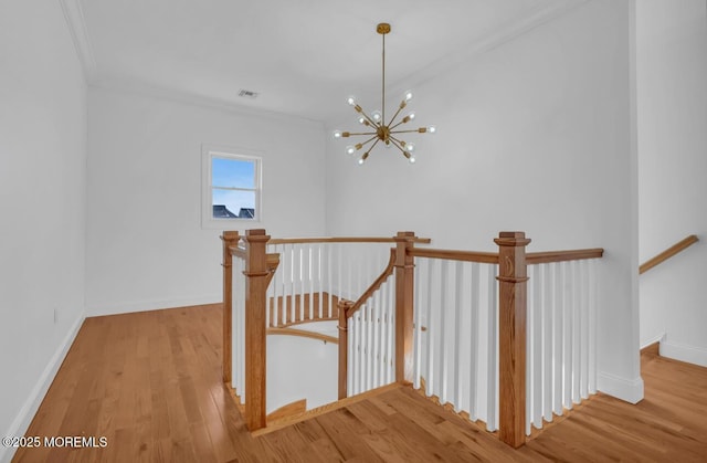 stairs featuring an inviting chandelier, wood-type flooring, and ornamental molding