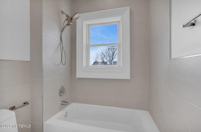 bathroom featuring tiled shower / bath and toilet