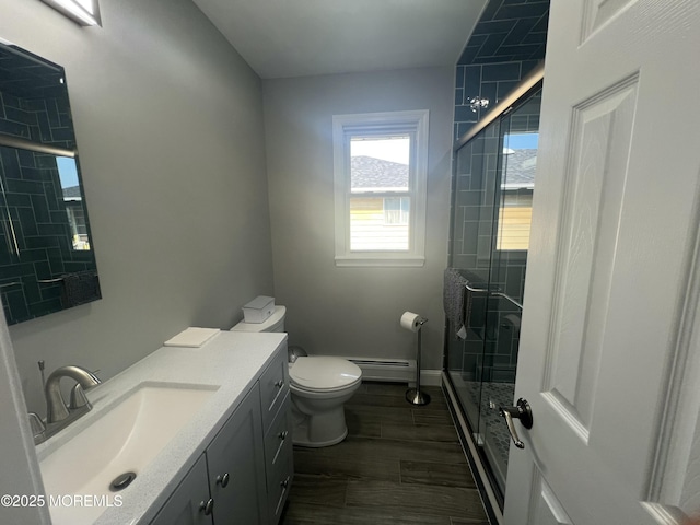 bathroom featuring vanity, toilet, a shower with shower door, and a baseboard heating unit