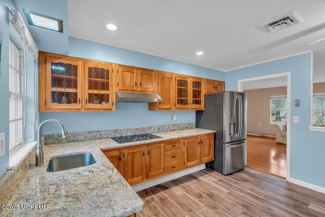 kitchen featuring sink, stainless steel fridge with ice dispenser, a baseboard heating unit, light hardwood / wood-style floors, and black electric cooktop