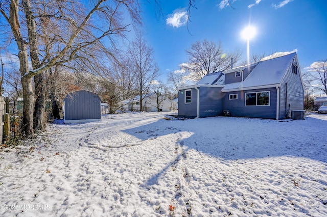 yard layered in snow featuring central AC unit and a shed