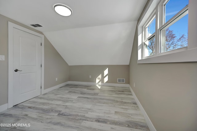 bonus room with light wood-type flooring and vaulted ceiling