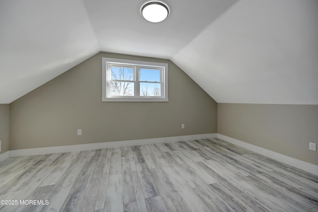 additional living space featuring vaulted ceiling and light wood-type flooring