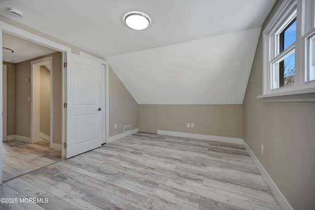 additional living space featuring light wood-type flooring and lofted ceiling