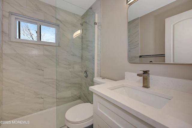 bathroom with tiled shower, vanity, and toilet