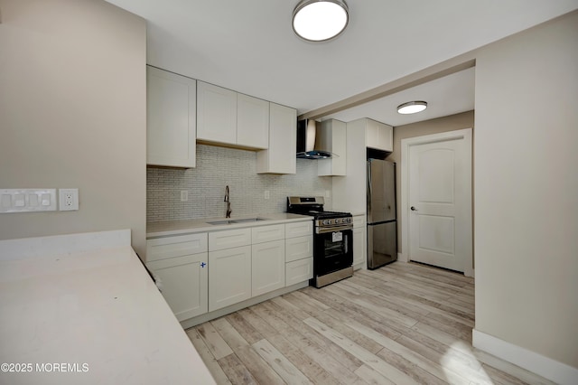 kitchen with white cabinetry, sink, wall chimney exhaust hood, appliances with stainless steel finishes, and light wood-type flooring