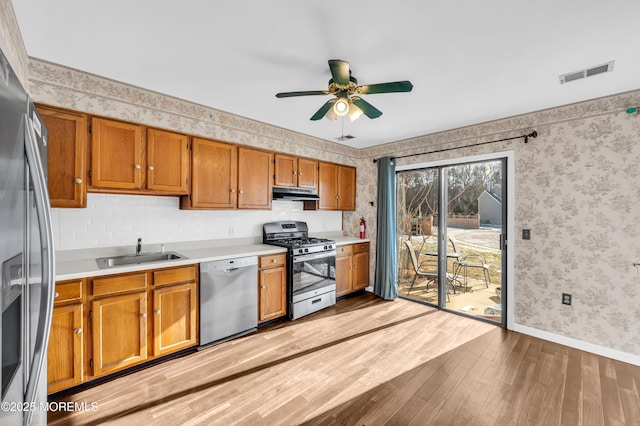 kitchen featuring appliances with stainless steel finishes, light hardwood / wood-style flooring, ceiling fan, and sink