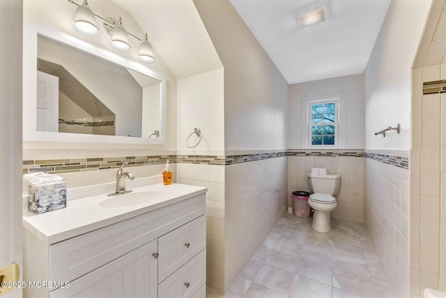 bathroom featuring tile patterned floors, vanity, toilet, and tile walls