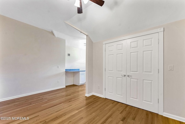 unfurnished bedroom with a closet, vaulted ceiling, ceiling fan, and hardwood / wood-style flooring