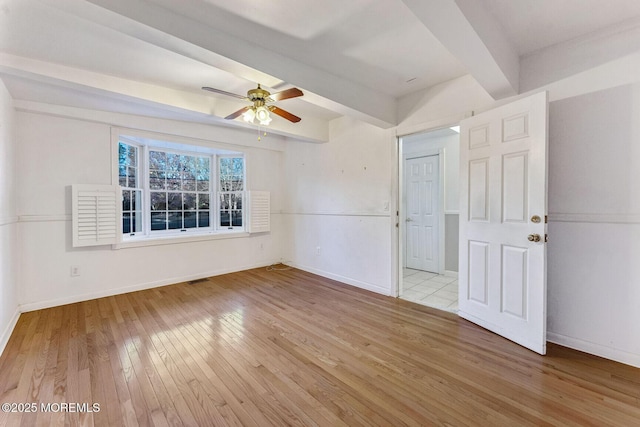 spare room featuring ceiling fan, light hardwood / wood-style flooring, and beamed ceiling