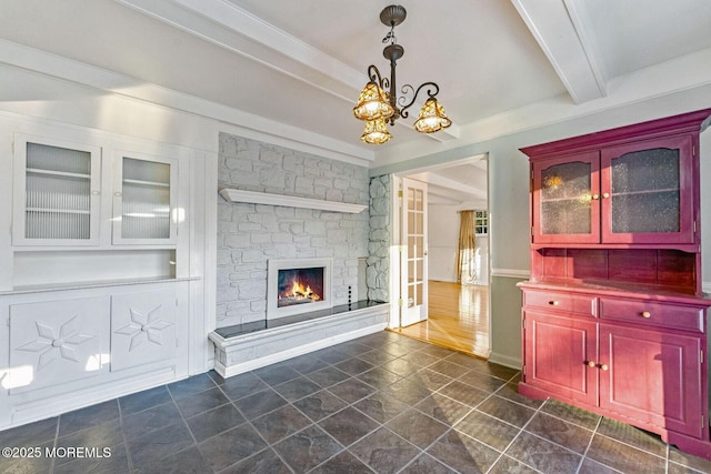 unfurnished living room featuring beam ceiling, a fireplace, and a chandelier