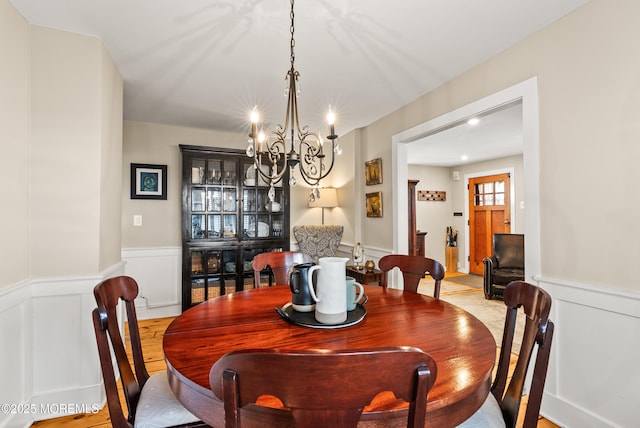 dining area featuring wainscoting, a decorative wall, and an inviting chandelier