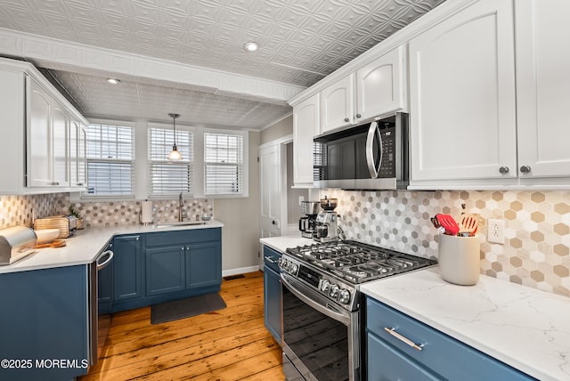 kitchen featuring an ornate ceiling, appliances with stainless steel finishes, white cabinetry, a sink, and blue cabinets