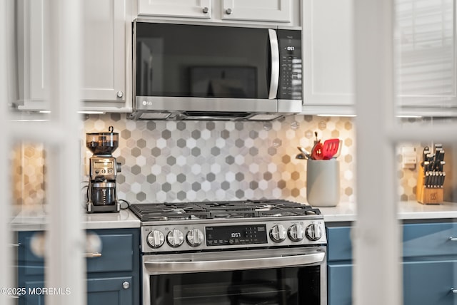 kitchen featuring blue cabinetry, backsplash, stainless steel appliances, and light countertops