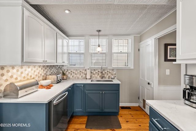 kitchen with white cabinets, dishwasher, decorative light fixtures, blue cabinetry, and a sink