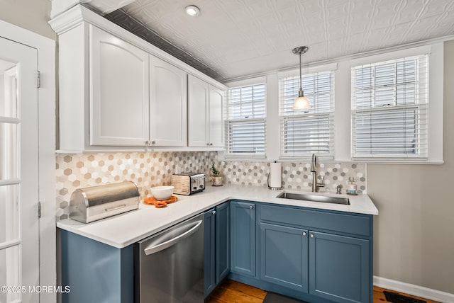 kitchen with tasteful backsplash, light countertops, a sink, blue cabinets, and dishwasher