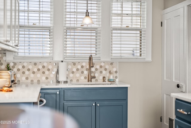 bar with tasteful backsplash, a healthy amount of sunlight, a sink, and hanging light fixtures