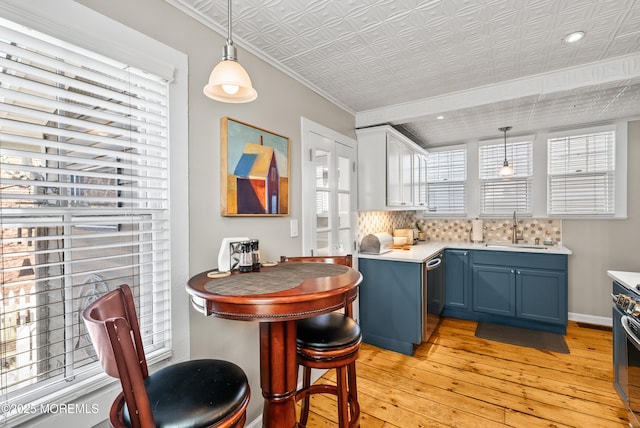 kitchen featuring light wood-style floors, a sink, light countertops, blue cabinetry, and stainless steel dishwasher