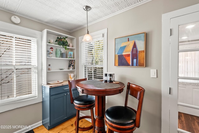 dining room with an ornate ceiling, crown molding, and light wood-style floors