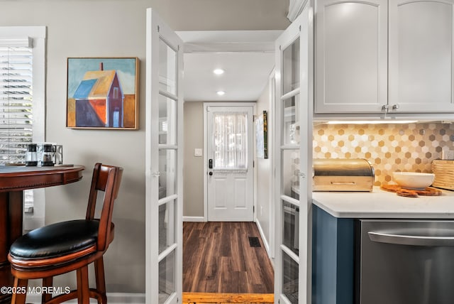 kitchen featuring dark wood-style flooring, light countertops, french doors, decorative backsplash, and dishwasher