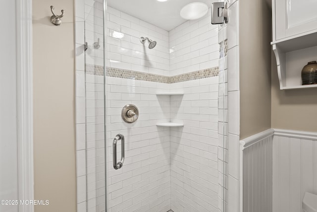 bathroom featuring wainscoting and a shower stall