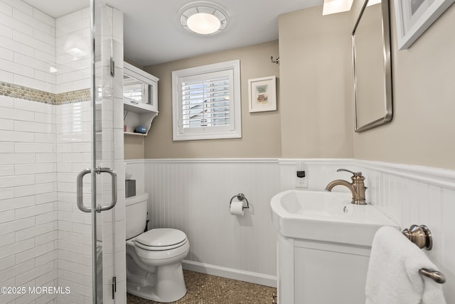 bathroom with a stall shower, wainscoting, vanity, and toilet