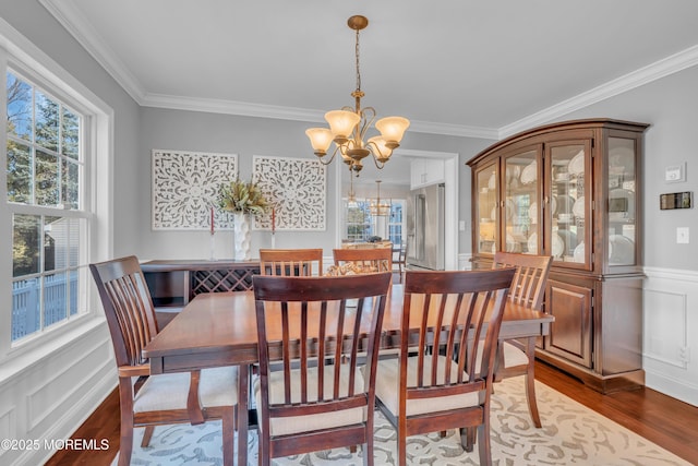 dining room with an inviting chandelier, hardwood / wood-style floors, a healthy amount of sunlight, and crown molding