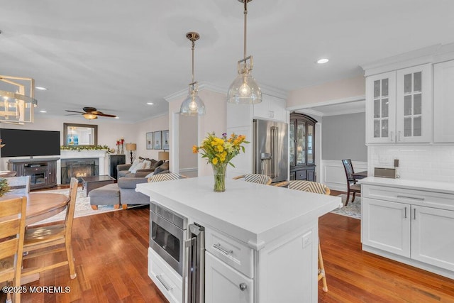 kitchen featuring stainless steel appliances, white cabinetry, ceiling fan, beverage cooler, and hanging light fixtures