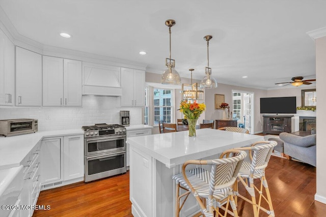 kitchen featuring range with two ovens, pendant lighting, light hardwood / wood-style flooring, and white cabinets