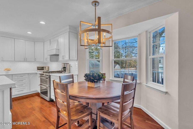 dining area with a notable chandelier, crown molding, and wood-type flooring