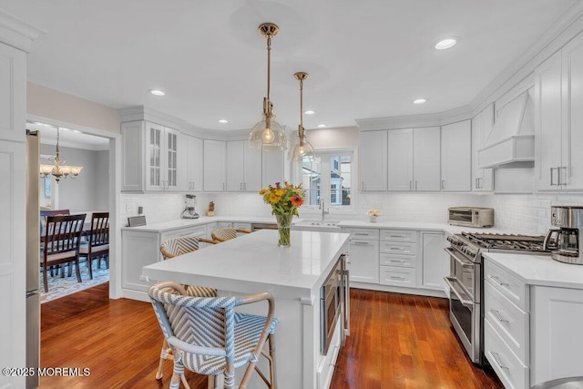 kitchen featuring white cabinets, hanging light fixtures, premium range hood, dark hardwood / wood-style flooring, and appliances with stainless steel finishes