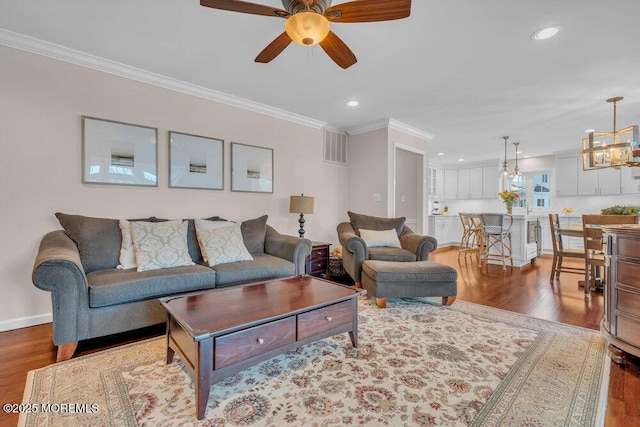 living room with ceiling fan with notable chandelier, light wood-type flooring, and ornamental molding