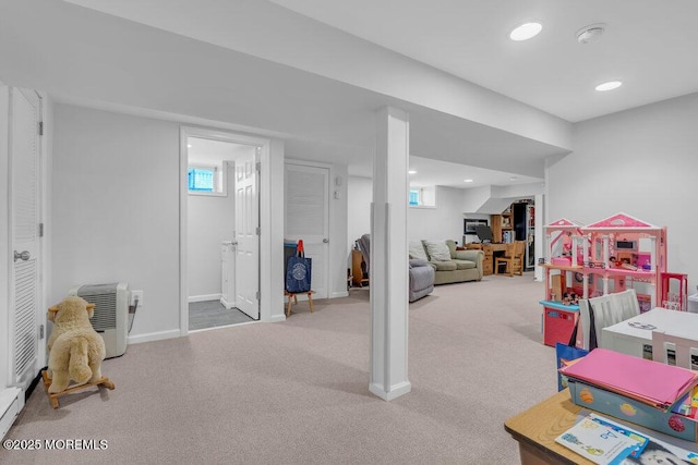 rec room with light colored carpet, a wealth of natural light, and a baseboard heating unit