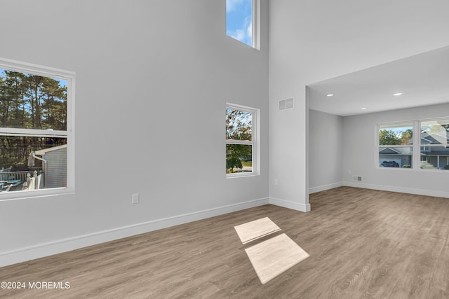 unfurnished living room with a high ceiling, light hardwood / wood-style flooring, and plenty of natural light