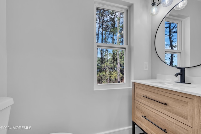 bathroom featuring vanity, a healthy amount of sunlight, and toilet