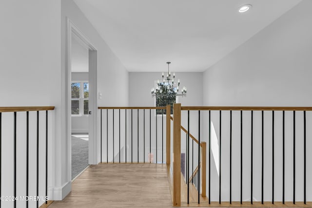 corridor with light hardwood / wood-style flooring and a chandelier