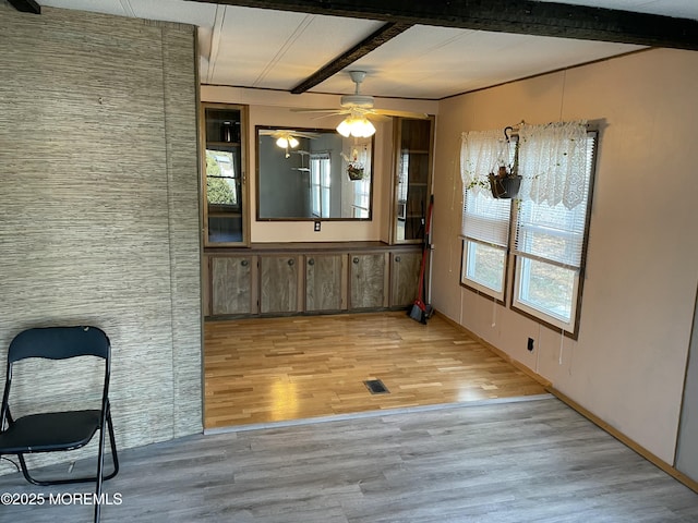 dining area with light wood finished floors, ceiling fan, and beamed ceiling