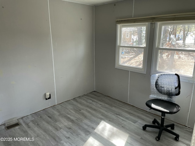 unfurnished office with plenty of natural light, visible vents, and wood finished floors