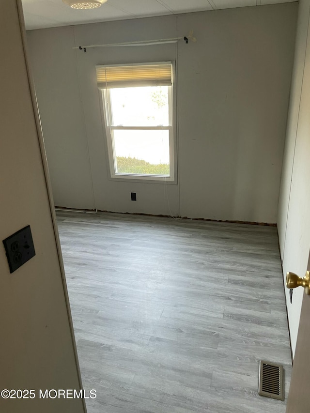 spare room with wood finished floors and visible vents